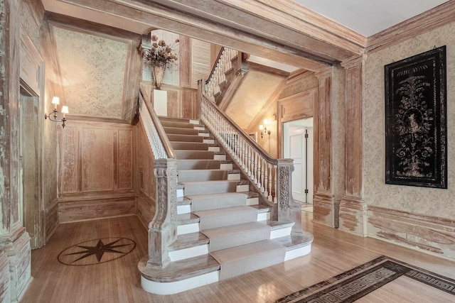 staircase with light hardwood / wood-style floors and ornamental molding