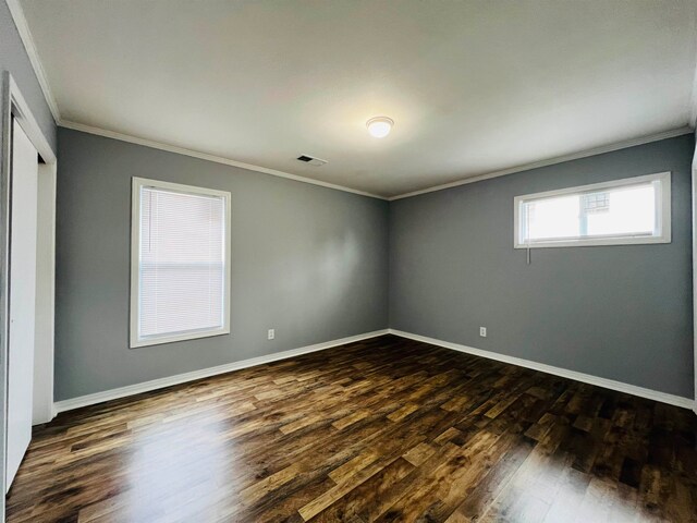 empty room with dark wood-type flooring and ornamental molding