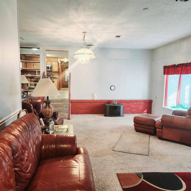 carpeted living room featuring an inviting chandelier and a textured ceiling