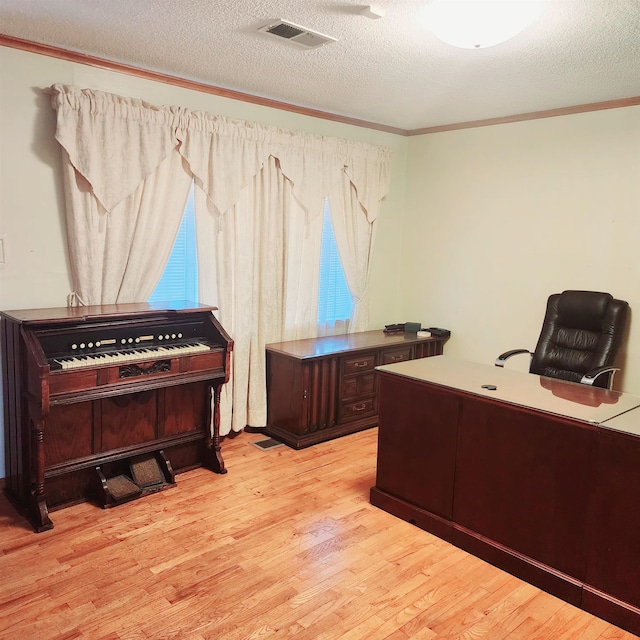 home office with ornamental molding, a textured ceiling, and light wood-type flooring