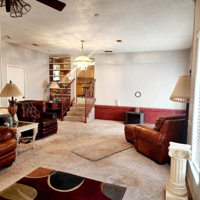 carpeted living room with a textured ceiling and ceiling fan with notable chandelier