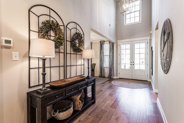 foyer entrance featuring dark hardwood / wood-style floors, a towering ceiling, and french doors