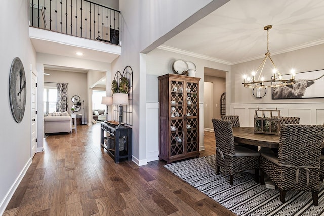 dining room featuring crown molding, dark hardwood / wood-style flooring, a towering ceiling, and a notable chandelier