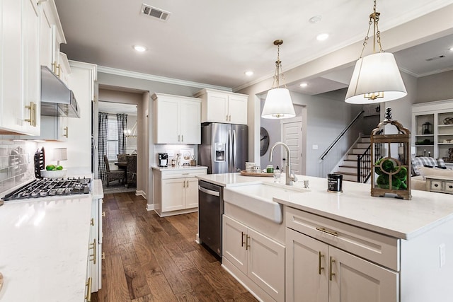 kitchen featuring dark wood-type flooring, hanging light fixtures, stainless steel appliances, a center island with sink, and white cabinets