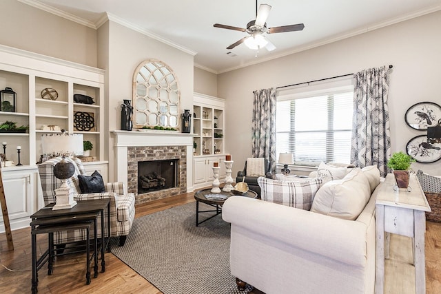 living room with hardwood / wood-style floors, ceiling fan, ornamental molding, and a fireplace