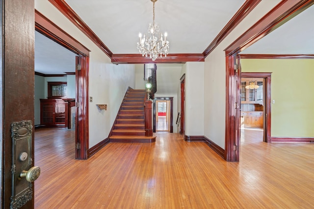 entrance foyer featuring light hardwood / wood-style flooring, crown molding, and a chandelier