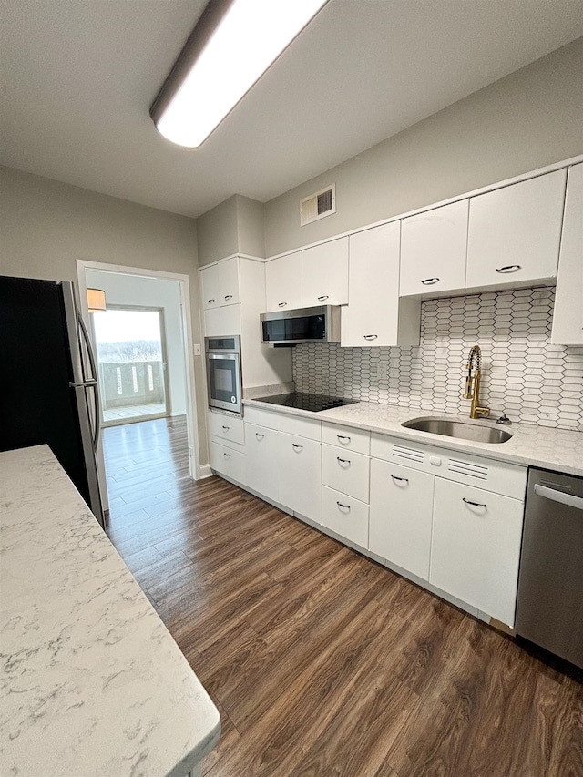 kitchen with backsplash, stainless steel appliances, white cabinetry, and dark hardwood / wood-style flooring