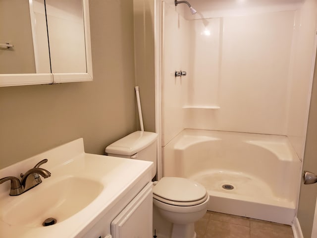 bathroom with tile flooring, toilet, a shower, and vanity with extensive cabinet space