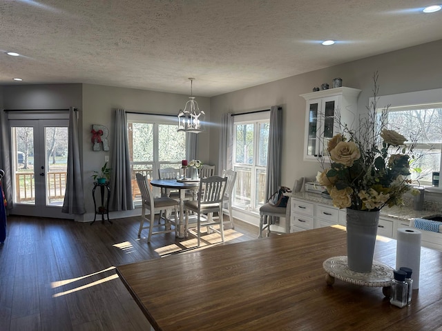 dining room with french doors, a textured ceiling, dark hardwood / wood-style flooring, and a notable chandelier