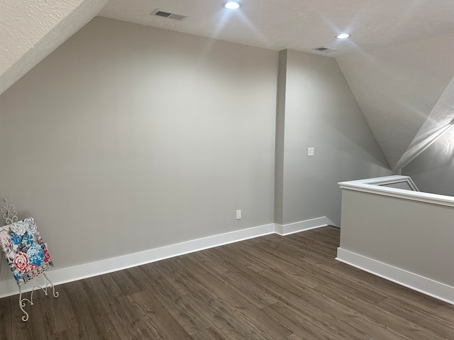 bonus room featuring a textured ceiling, lofted ceiling, and dark hardwood / wood-style flooring