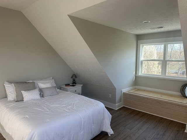 bedroom with dark hardwood / wood-style floors, vaulted ceiling, and a textured ceiling