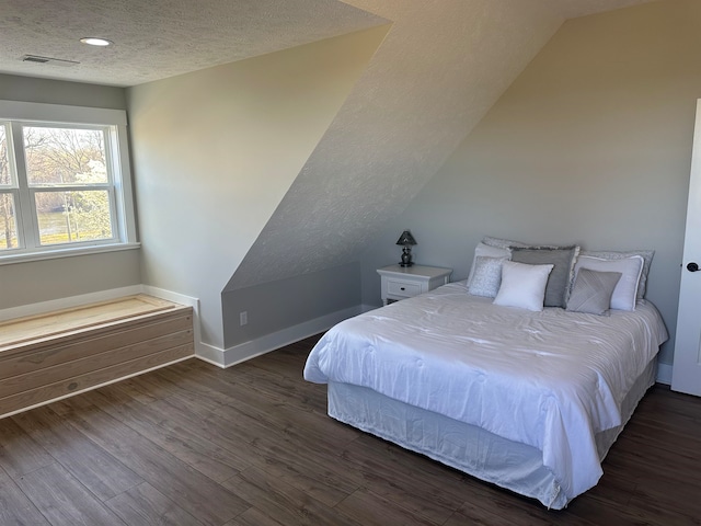 bedroom featuring lofted ceiling, a textured ceiling, and dark wood-type flooring