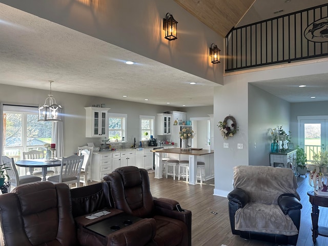 living room featuring an inviting chandelier, sink, a textured ceiling, vaulted ceiling, and dark hardwood / wood-style flooring