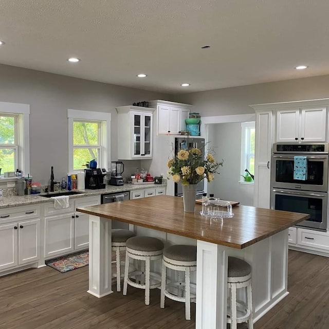 kitchen with white cabinetry, sink, stainless steel appliances, a kitchen island, and a breakfast bar area