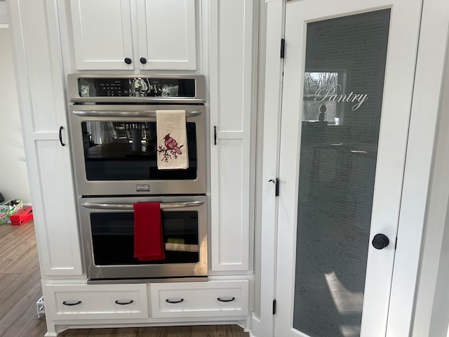 kitchen featuring white cabinets, wood-type flooring, and double oven