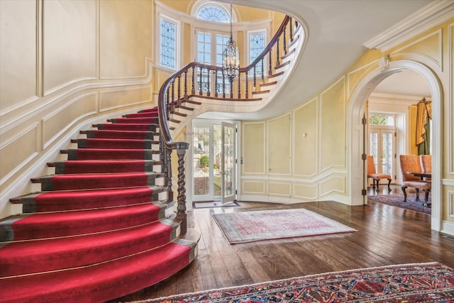 foyer with crown molding, dark hardwood / wood-style floors, a healthy amount of sunlight, and a chandelier