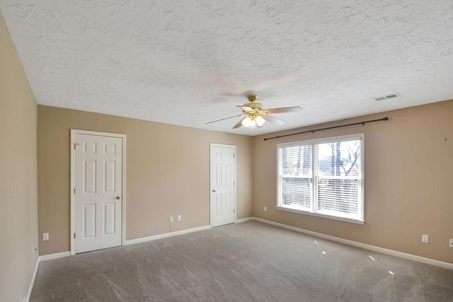 empty room with a textured ceiling, ceiling fan, and dark colored carpet