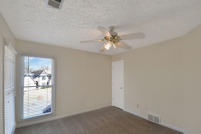 unfurnished room featuring a healthy amount of sunlight, dark carpet, and ceiling fan