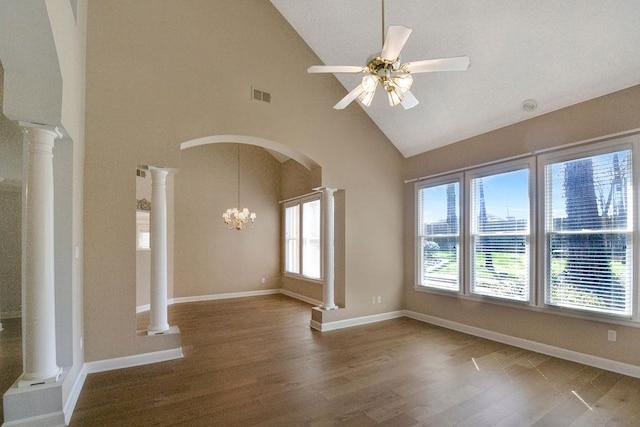 empty room featuring ceiling fan with notable chandelier, plenty of natural light, dark hardwood / wood-style flooring, and decorative columns