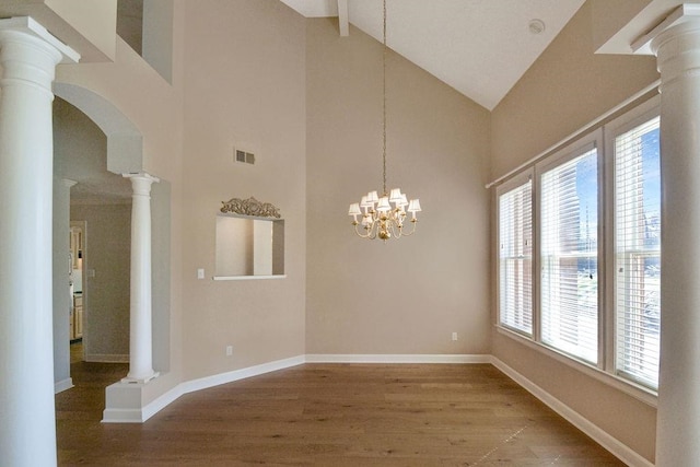 spare room featuring high vaulted ceiling, light hardwood / wood-style flooring, ornate columns, and an inviting chandelier