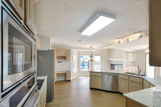 kitchen featuring stainless steel appliances, light hardwood / wood-style floors, light stone counters, sink, and a notable chandelier