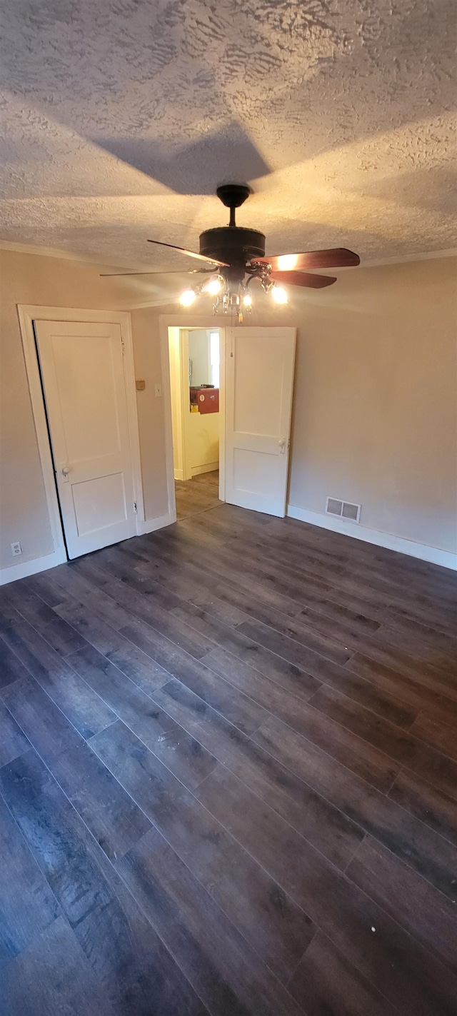 unfurnished bedroom with ceiling fan, a textured ceiling, and dark hardwood / wood-style floors