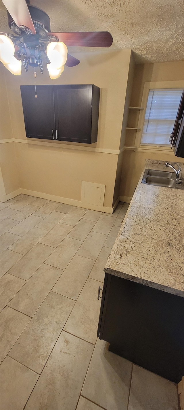 interior space with ceiling fan, sink, light stone countertops, and light tile floors