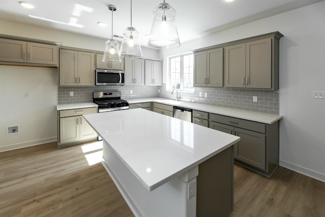 kitchen with stainless steel appliances, decorative light fixtures, a kitchen island, dark hardwood / wood-style floors, and decorative backsplash