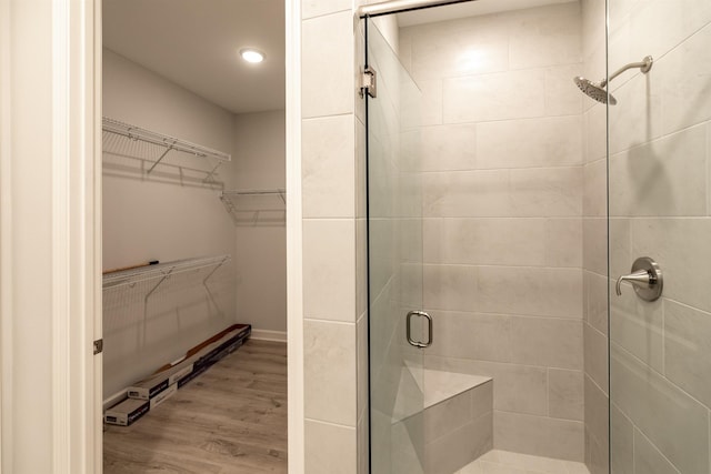 bathroom with wood-type flooring and a shower with shower door