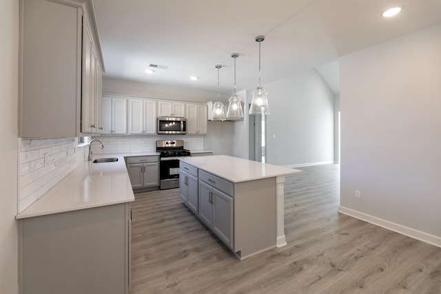 kitchen featuring appliances with stainless steel finishes, tasteful backsplash, pendant lighting, a kitchen island, and sink