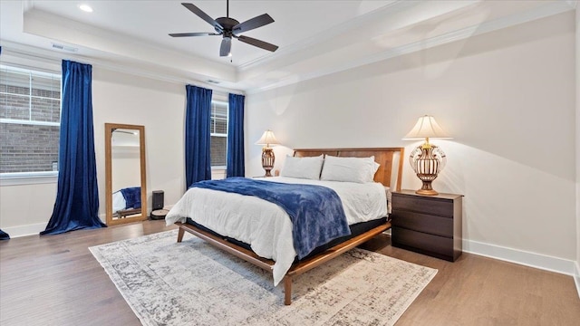 bedroom featuring ceiling fan, crown molding, a raised ceiling, and hardwood / wood-style flooring