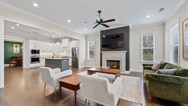 living room with ceiling fan, ornamental molding, light hardwood / wood-style floors, and sink