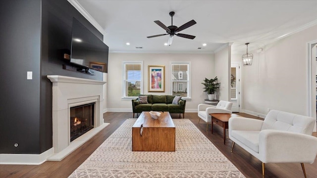 living room with ornamental molding, dark hardwood / wood-style floors, and ceiling fan with notable chandelier