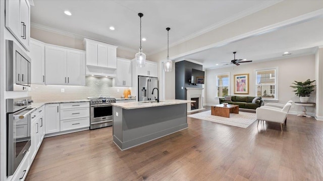 kitchen with a kitchen island with sink, pendant lighting, ceiling fan, dark wood-type flooring, and high quality appliances