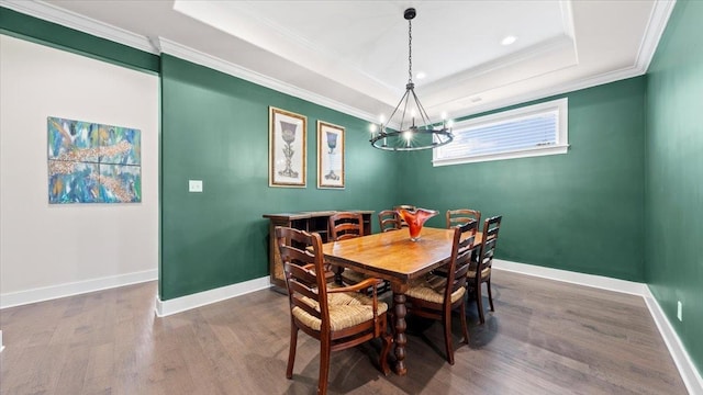 dining space featuring crown molding, dark hardwood / wood-style floors, a chandelier, and a raised ceiling