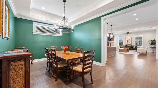 dining space with ornamental molding, dark hardwood / wood-style floors, a tray ceiling, and ceiling fan with notable chandelier