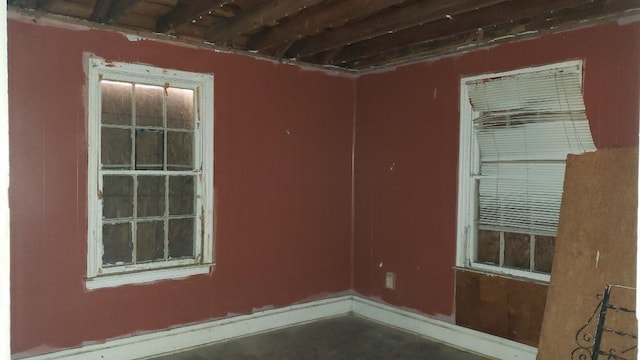 empty room with beamed ceiling and concrete floors