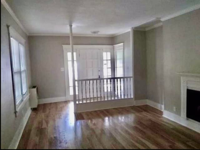 unfurnished living room with dark wood-type flooring and crown molding