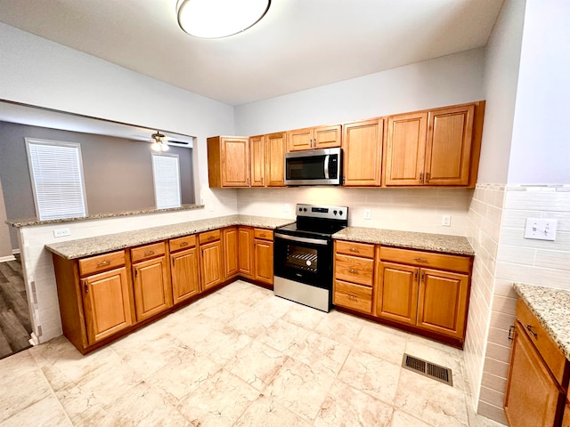 kitchen featuring ceiling fan, stainless steel appliances, light stone counters, and light tile floors