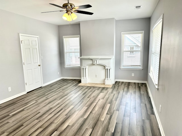 unfurnished living room with ceiling fan, a wealth of natural light, and hardwood / wood-style flooring