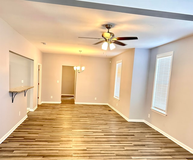 spare room featuring ceiling fan with notable chandelier and hardwood / wood-style flooring