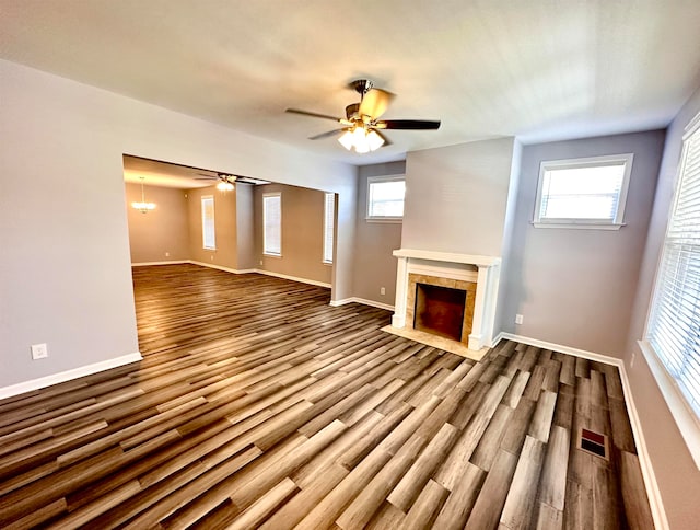 unfurnished living room with ceiling fan, a tile fireplace, a wealth of natural light, and hardwood / wood-style floors