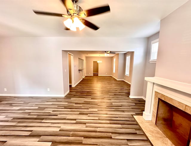 unfurnished living room featuring ceiling fan, a fireplace, and light wood-type flooring