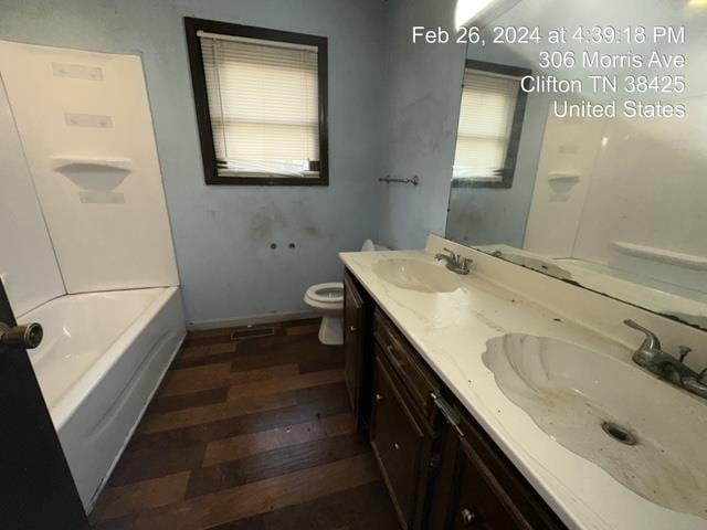 bathroom featuring toilet, oversized vanity, hardwood / wood-style floors, and double sink