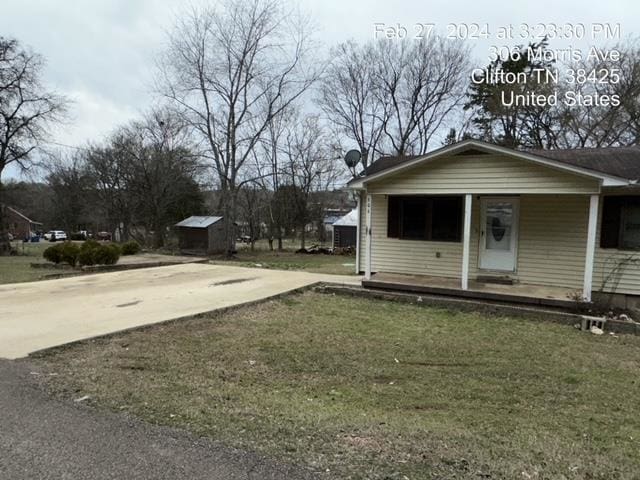 view of home's exterior with a yard, a porch, and an outdoor structure