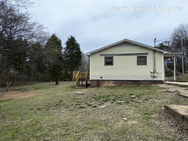 view of home's exterior with a wooden deck and a yard