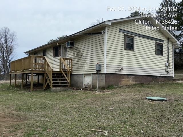 rear view of property featuring a lawn, a deck, and a wall mounted air conditioner