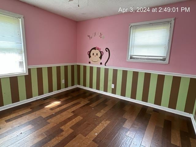 unfurnished room with a textured ceiling and dark wood-type flooring