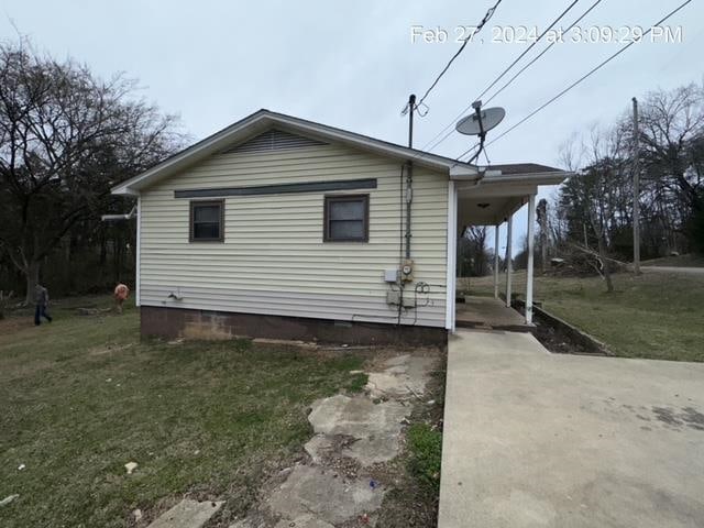 view of side of property featuring a carport and a lawn