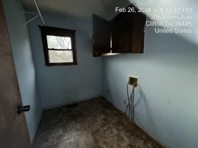 laundry area featuring washer hookup, cabinets, and dark tile floors